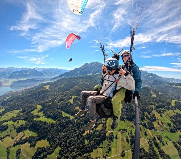 Tandem paragliding over green hills near Mt. Pilatus, Switzerland